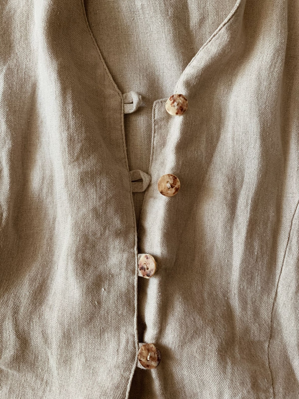 neutral linen vest with coconut shell buttons